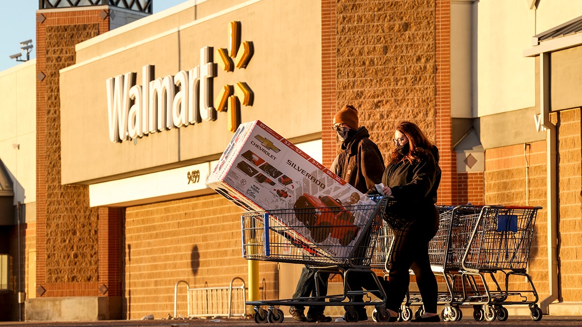 Black Friday shoppers walk out of Walmart with a full shopping cart on November 26, 2021, in Westminster, Colorado.