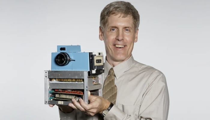 Steve Sasson holds his invention of first hanheld digital camera. — George Eastman Museum